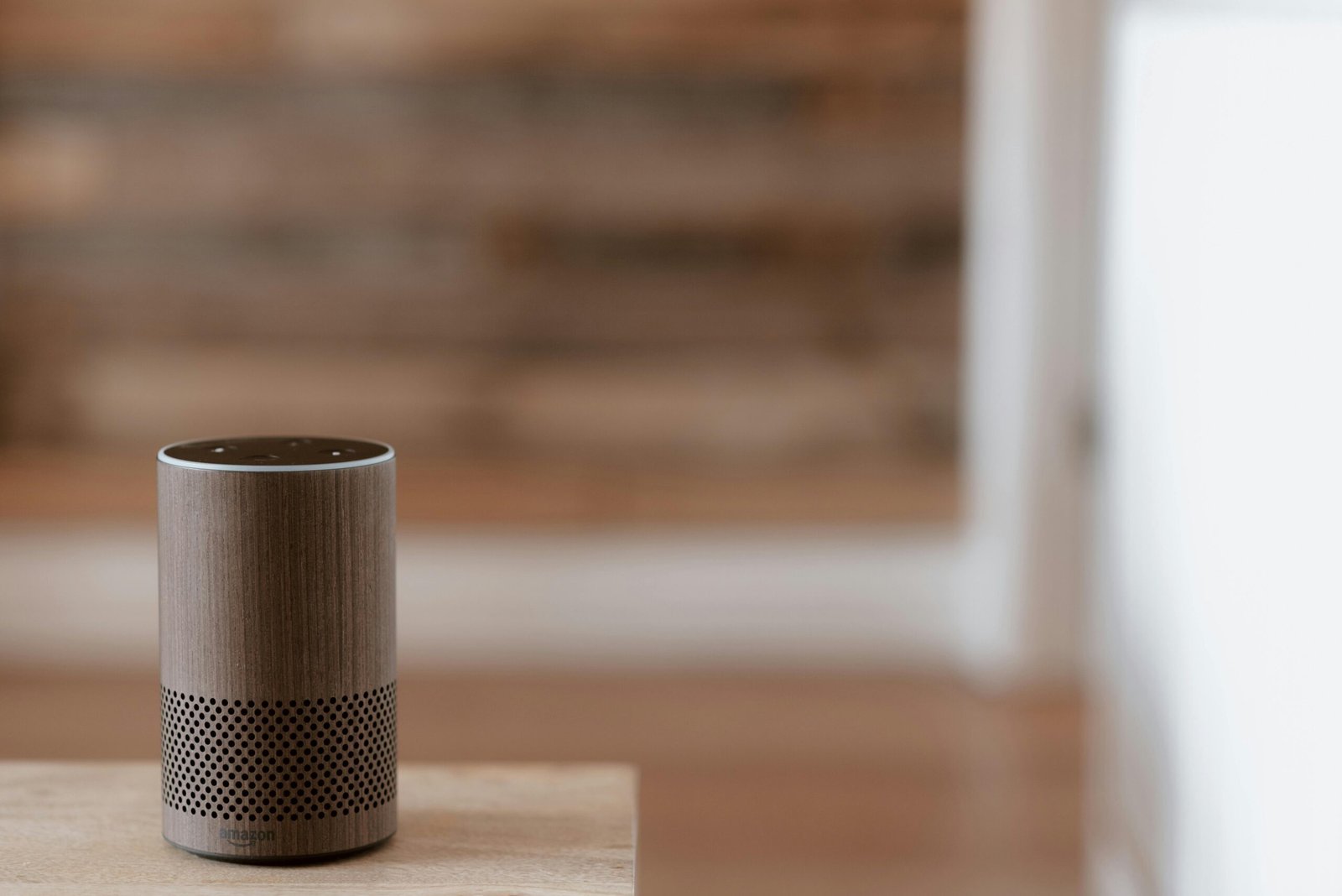 A close-up shot of a voice assistant device next to a cozy bedside lamp.